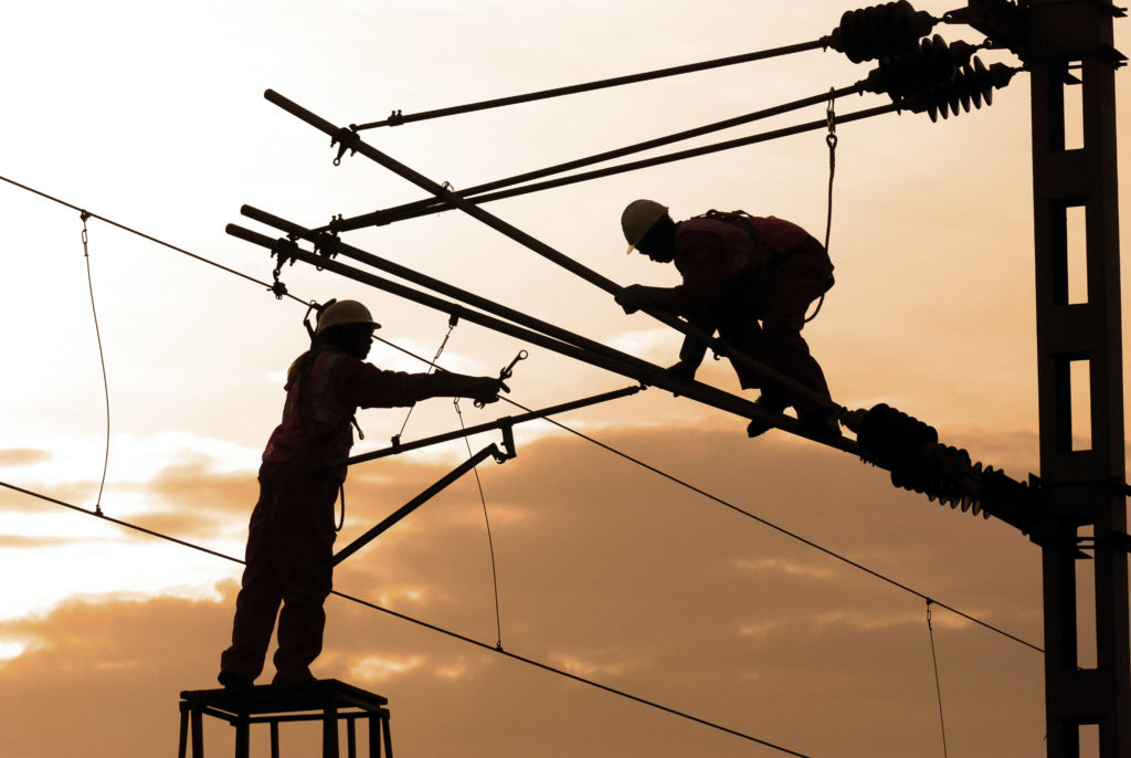 Men working on telephone wires at sunset